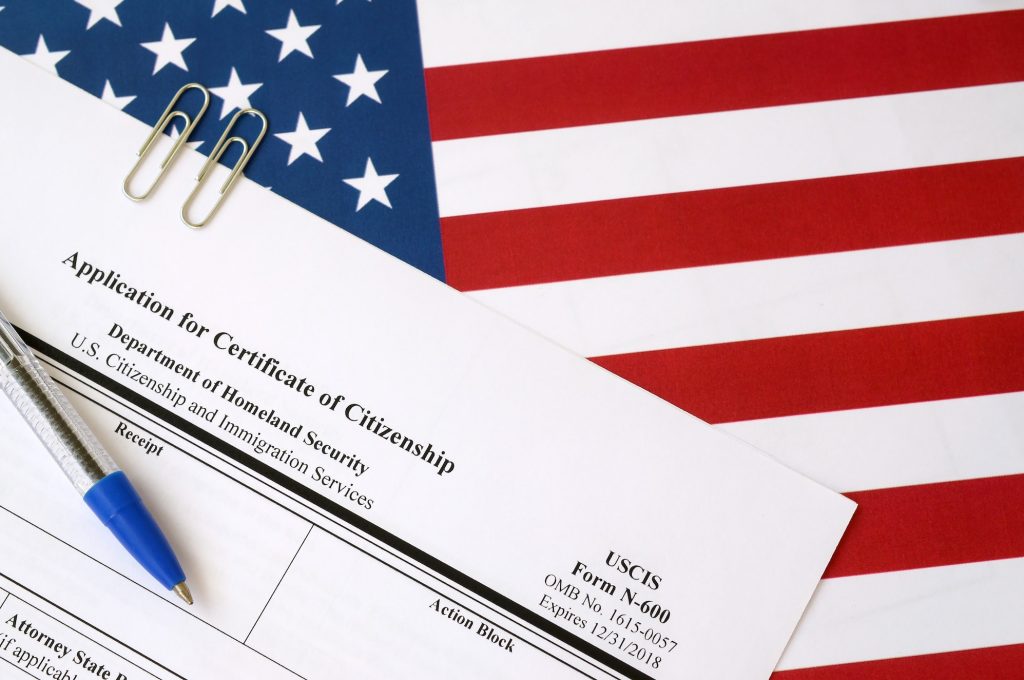 N-600 Application for Certificate of Citizenship blank form lies on United States flag with blue pen